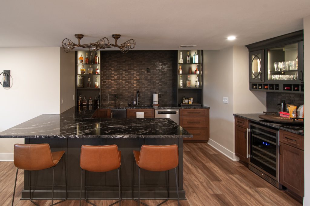 Picture of a Wexford, PA, traditional-style basement remodel, accented by a bar to entertain guests using warmer tones.