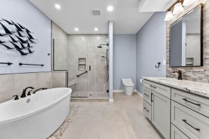 This Stunning Spa-Inspired Pittsburgh Bathroom Remodel Features a Luxurious Freestanding Soaking Tub Sitting on a Pebbled Tile, Spacious Glass-Enclosed Walk-In Shower with Custom Tile, and a Sleek Double Vanity with Granite Countertops and Elegant Bronze Fixtures. Modern Finishes and Calming Color Tones Make This Pittsburgh Bathroom a Serene Retreat.