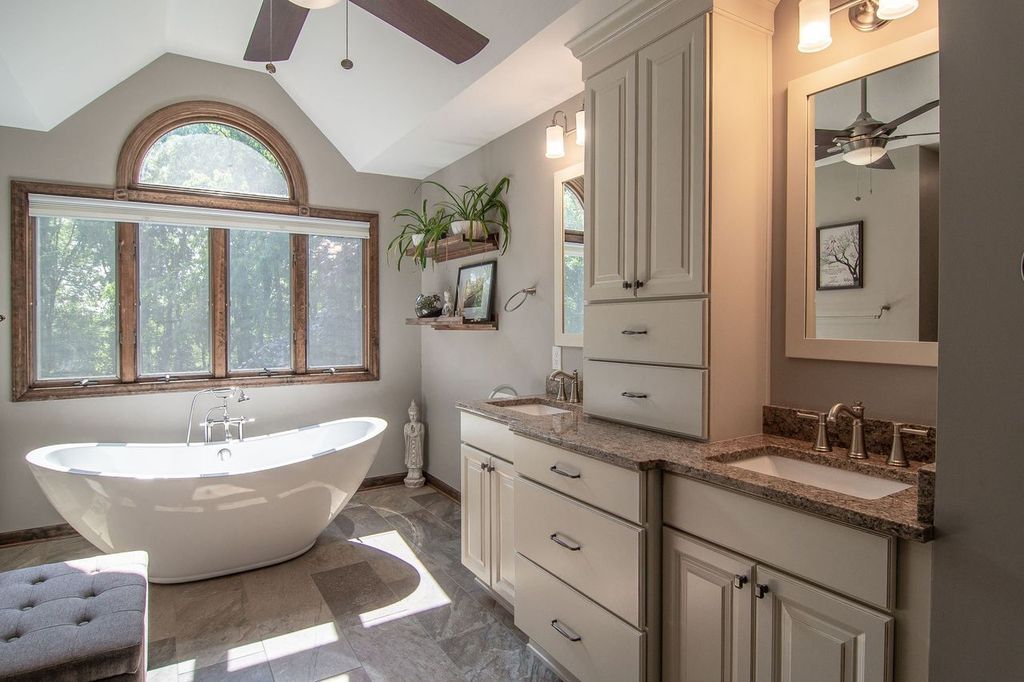 This South Park Master Bathroom Featuring a Free-Standing Soaking Tub, Double Vanity Which Offers Ample Storage, Custom Cabinetry and Granite Countertops Set Beneath a Large Arched Window That Fills the Space with Natural Light Making this Sophisticated Bathroom a Perfect Spa-Like Retreat.
