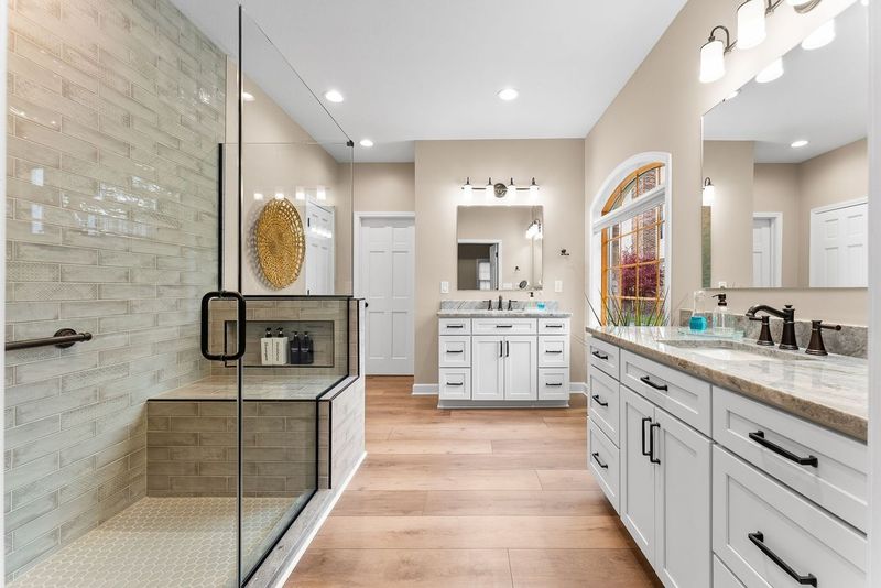 This Stunning Squirrel Hill Master Bathroom Includes a Large Walk-In Shower with Glass Enclosure, Built-In Bench and Custom Tile Surround Combining Luxury and Functionality with its Spacious Layout and High-End Finishes.