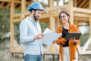 A designer and a builder reviewing design-build plans on site.
