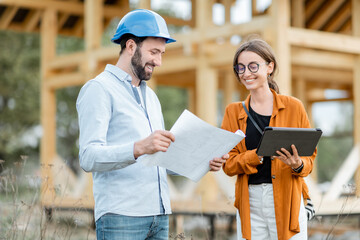 A designer and a builder reviewing design-build plans on site.
