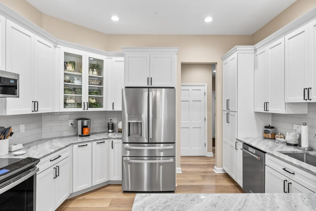 Modern Beaver Falls Kitchen Showing White Shaker-Style Cabinets, White Granite Countertops, White Subway Backsplash With Deco Tiles and Light Wood Floor.