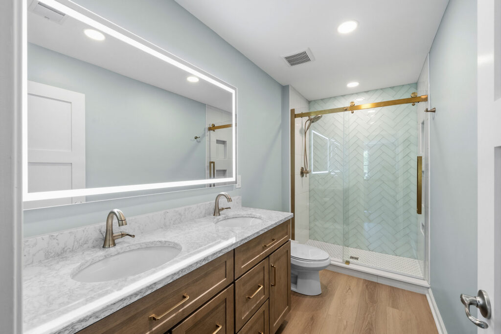 Transitional Style Gibsonia Bathroom with Wood-Tone Shaker-Style Vanity, White Quartz Countertop with Grey Veining and White Tile Shower with Hexagon Mosaic Floor