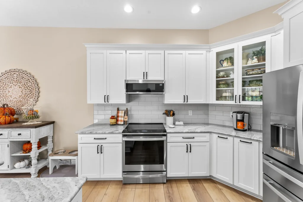 Modern Beaver Falls Kitchen Showing White Shaker-Style Cabinets, White Granite Countertops, White Subway Backsplash With Deco Tiles and Light Wood Floor.