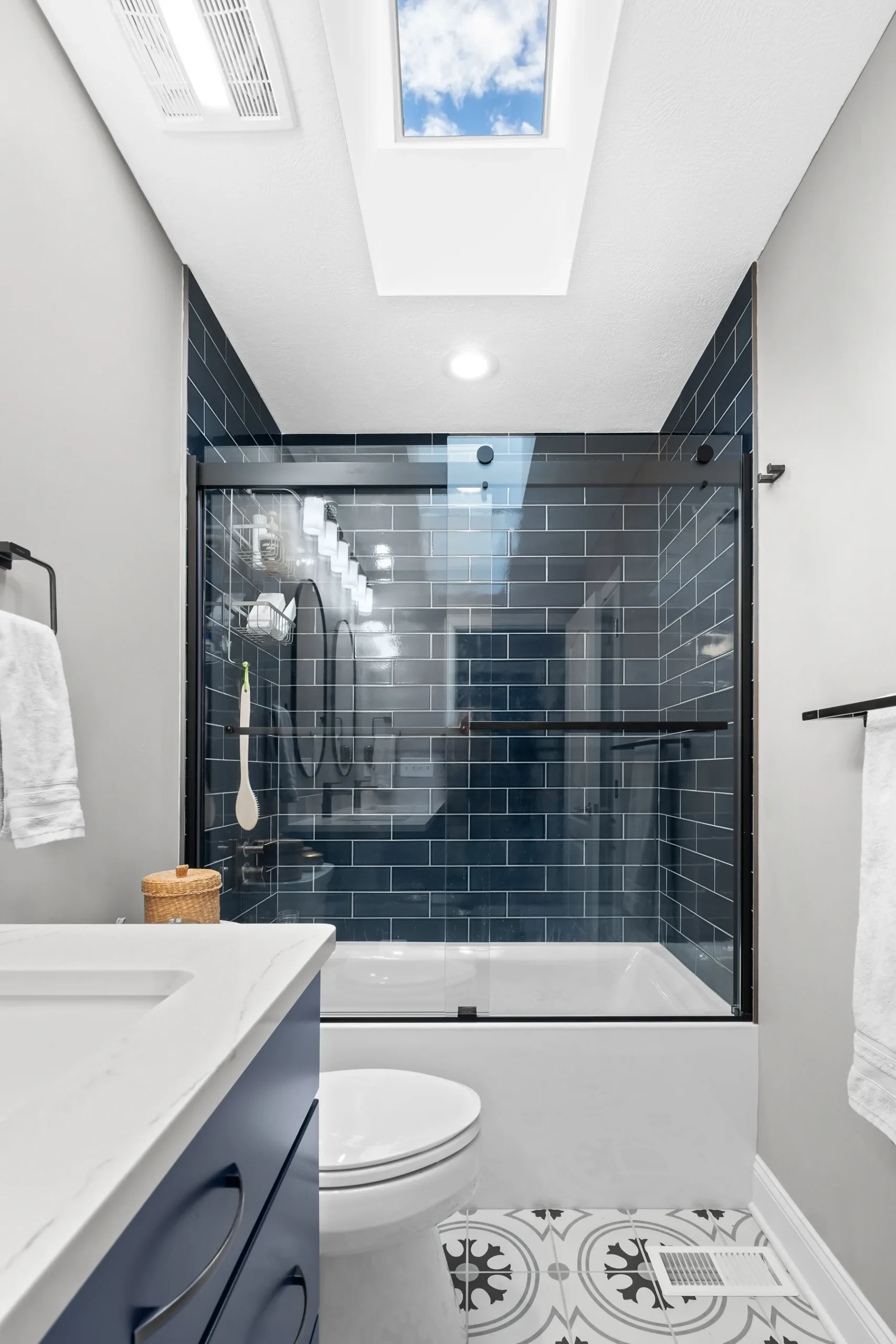 Transitional McCandless
Master Bathroom Showing Navy Blue Vanity With White
Quartz Countertop, Tub With Navy Blue Subway Tile and Matte Black Shower Door
and Fixtures