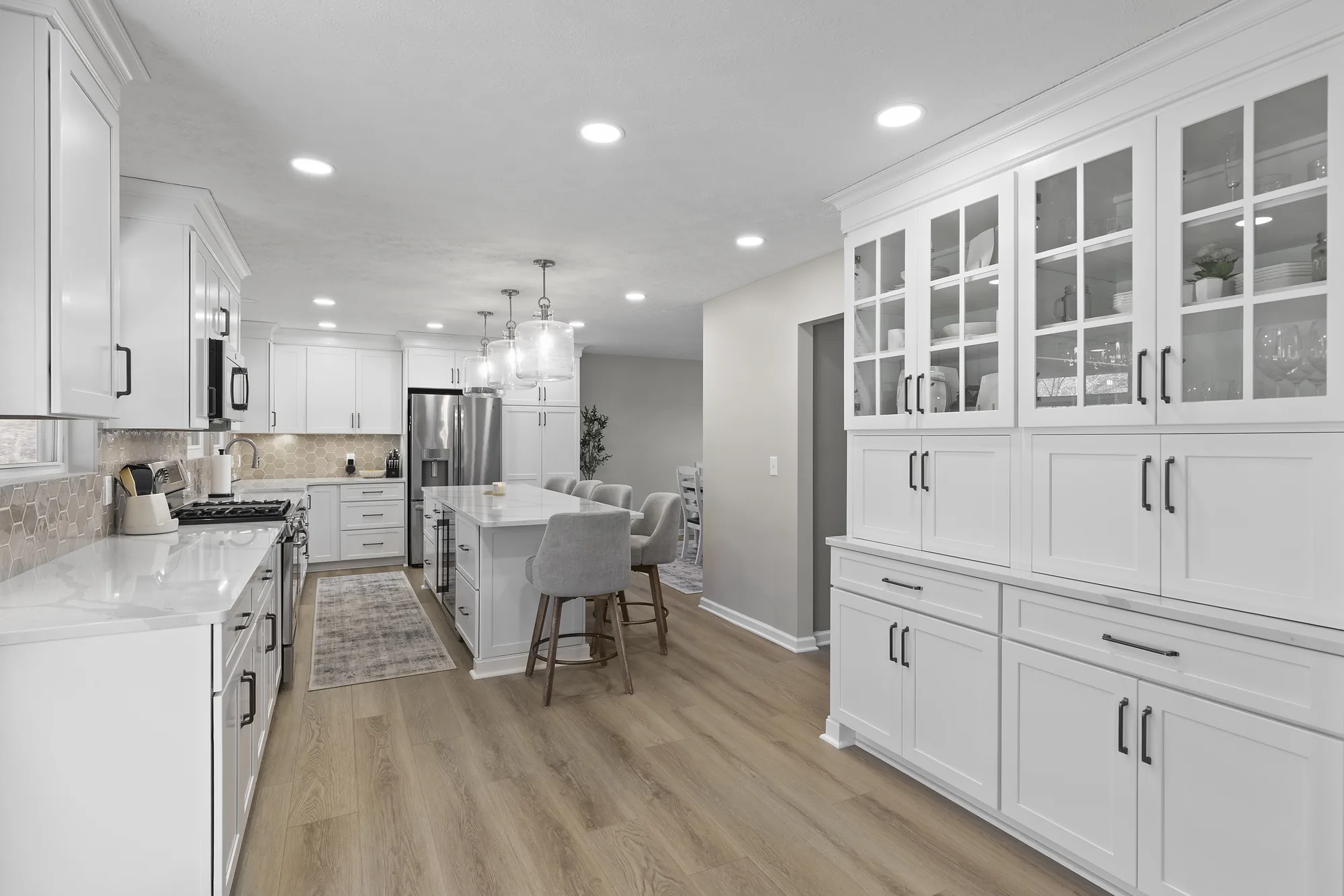 Modern Transitional Coraopolis Kitchen Featuring White Shaker Cabinetry, Light
Quartz Countertops, Warm L
uxury Vinyl Flooring and a Neutral Backsplash.