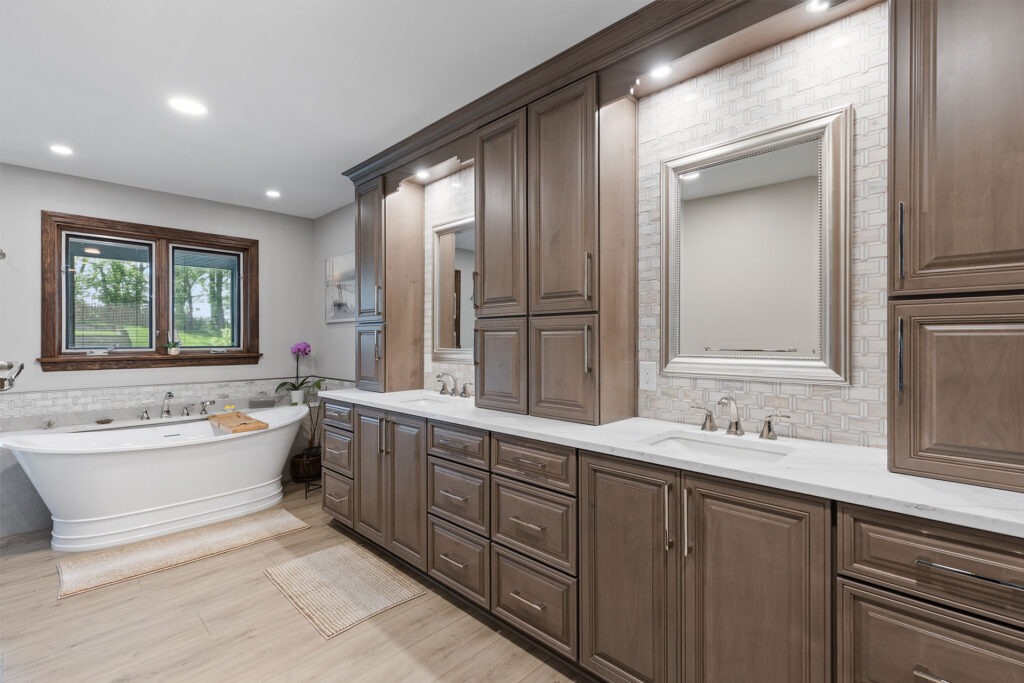 Traditional Style McMurray Bathroom with Stained Raised Panel Cabinets, White Quartz Countertops, Cool Grey Marble Backsplash and Freestanding Soaking Tub