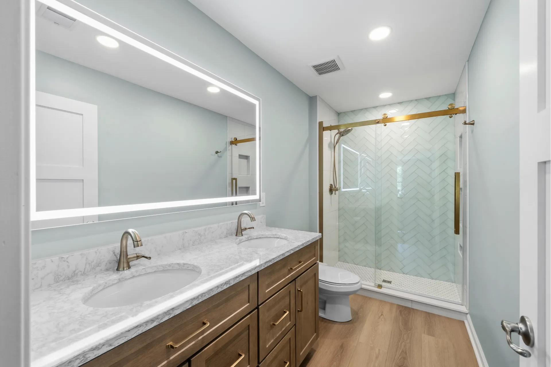 Transitional Style Gibsonia Bathroom with Wood-Tone Shaker-Style Vanity, White Quartz Countertop with Grey Veining and White Tile Shower with Hexagon Mosaic Floor