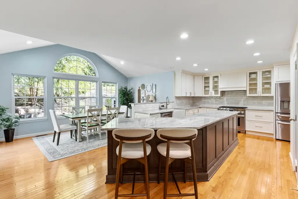 Transitional Kitchen with white cabinets and dark brown accent island, warm gray quartz countertop with white and brown veining, off white subway tile backsplash