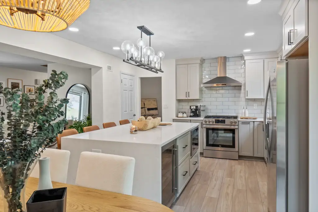 Modern Murrysville Kitchen Featuring Light Gray Shaker-Style Cabinets, White Quartz Countertops With Subway Backsplash and Light Wood Flooring.