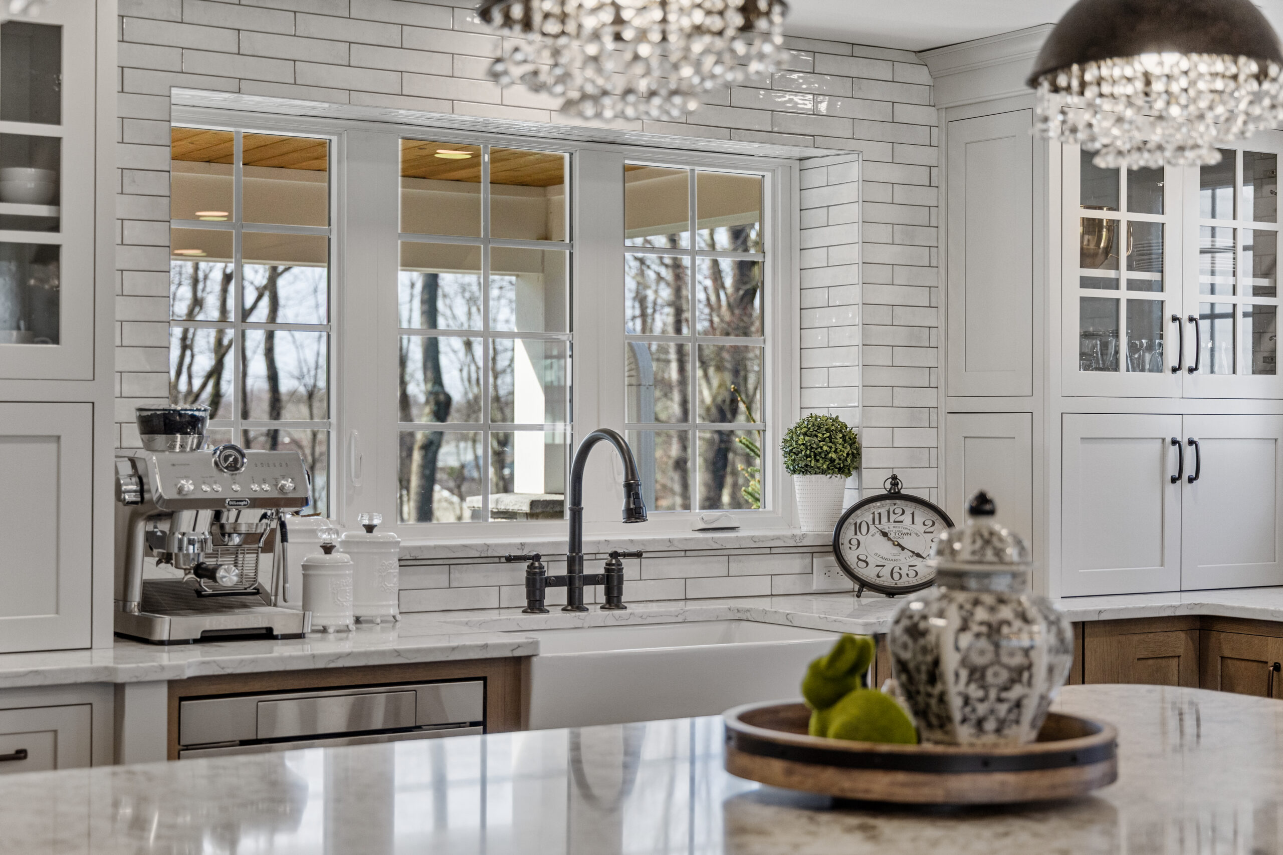 Bright Transitional Farmhouse Kitchen With Mix of White, Light Gray and Stain Shaker Cabinets, Quartz Countertop With Veining, Hardwood Floors and a Large Island.