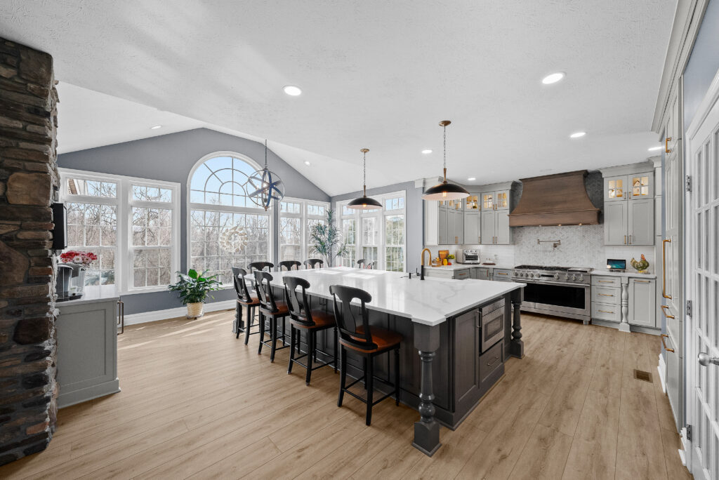 Bright Airy Baldwin Kitchen Showing a Light Quartz Countertop With Veining, Warm Tone Luxury Vinyl Flooring and Large Gray Island