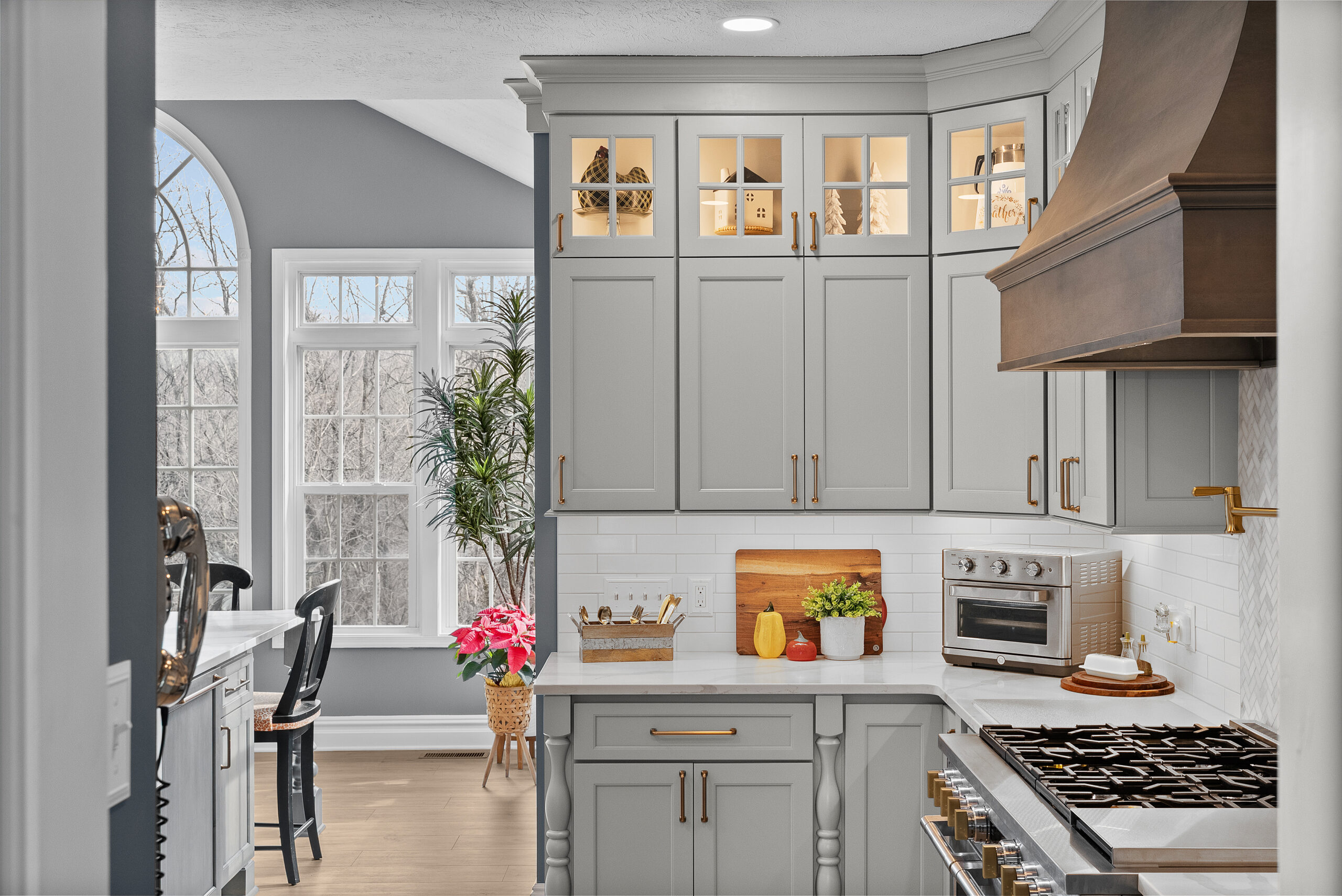 Bright Airy Baldwin Kitchen Showing a Light Quartz Countertop With Veining, Warm Tone Luxury Vinyl Flooring and Large Gray Island