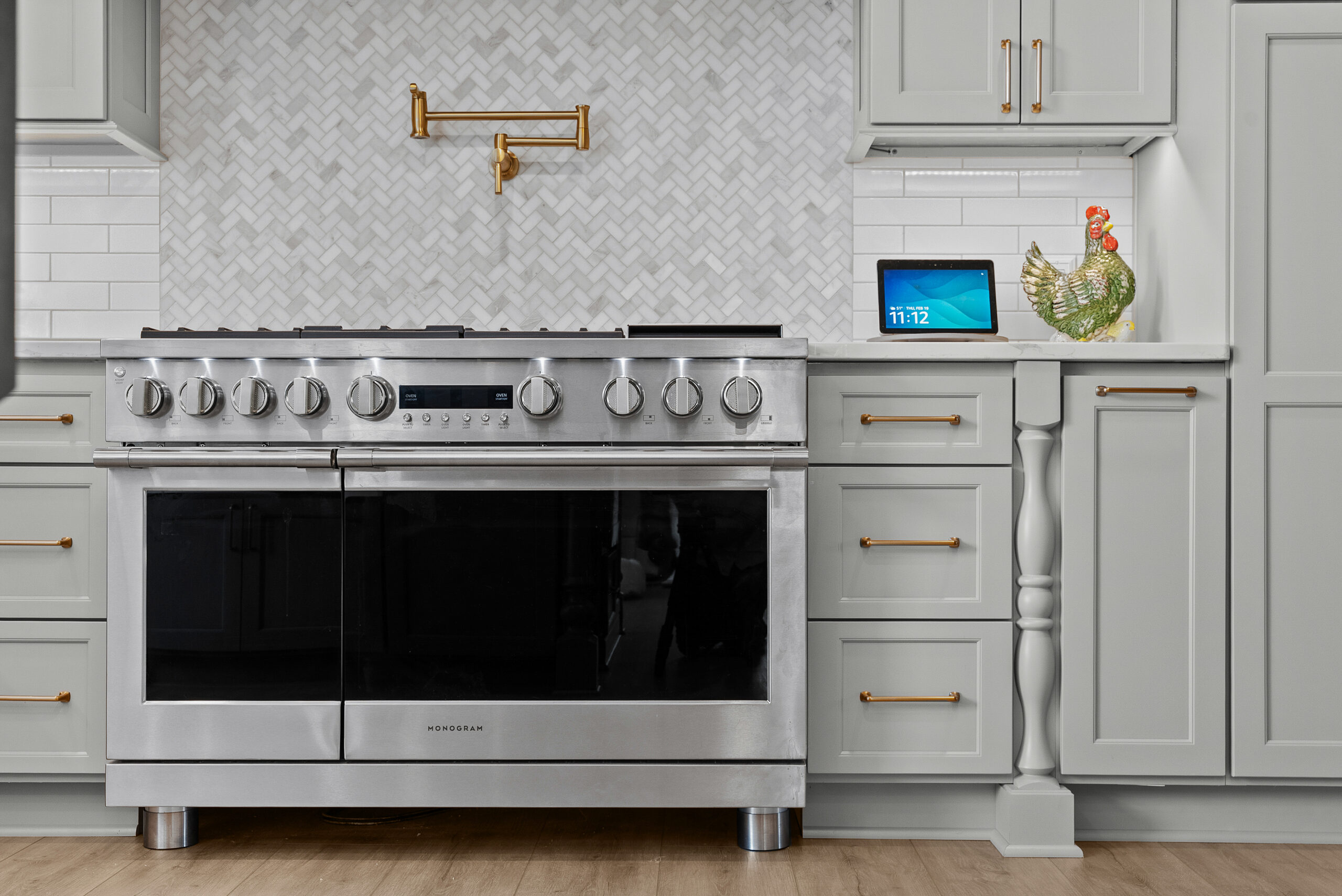 Bright Airy Baldwin Kitchen Showing a Light Quartz Countertop With Veining, Warm Tone Luxury Vinyl Flooring and Large Gray Island