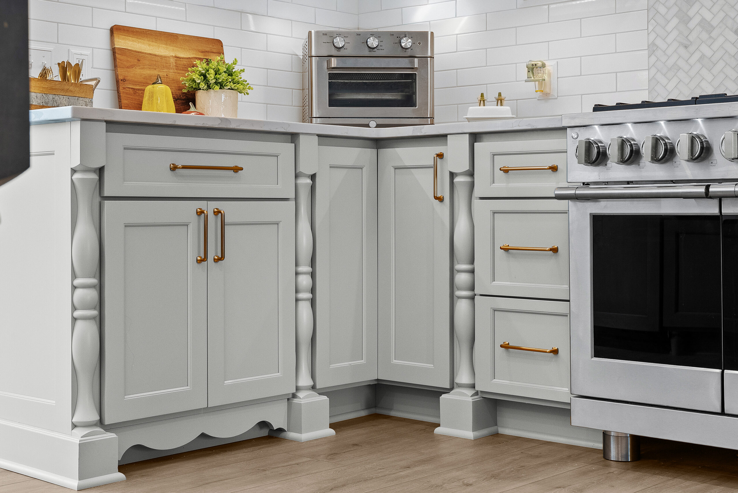 Bright Airy Baldwin Kitchen Showing a Light Quartz Countertop With Veining, Warm Tone Luxury Vinyl Flooring and Large Gray Island
