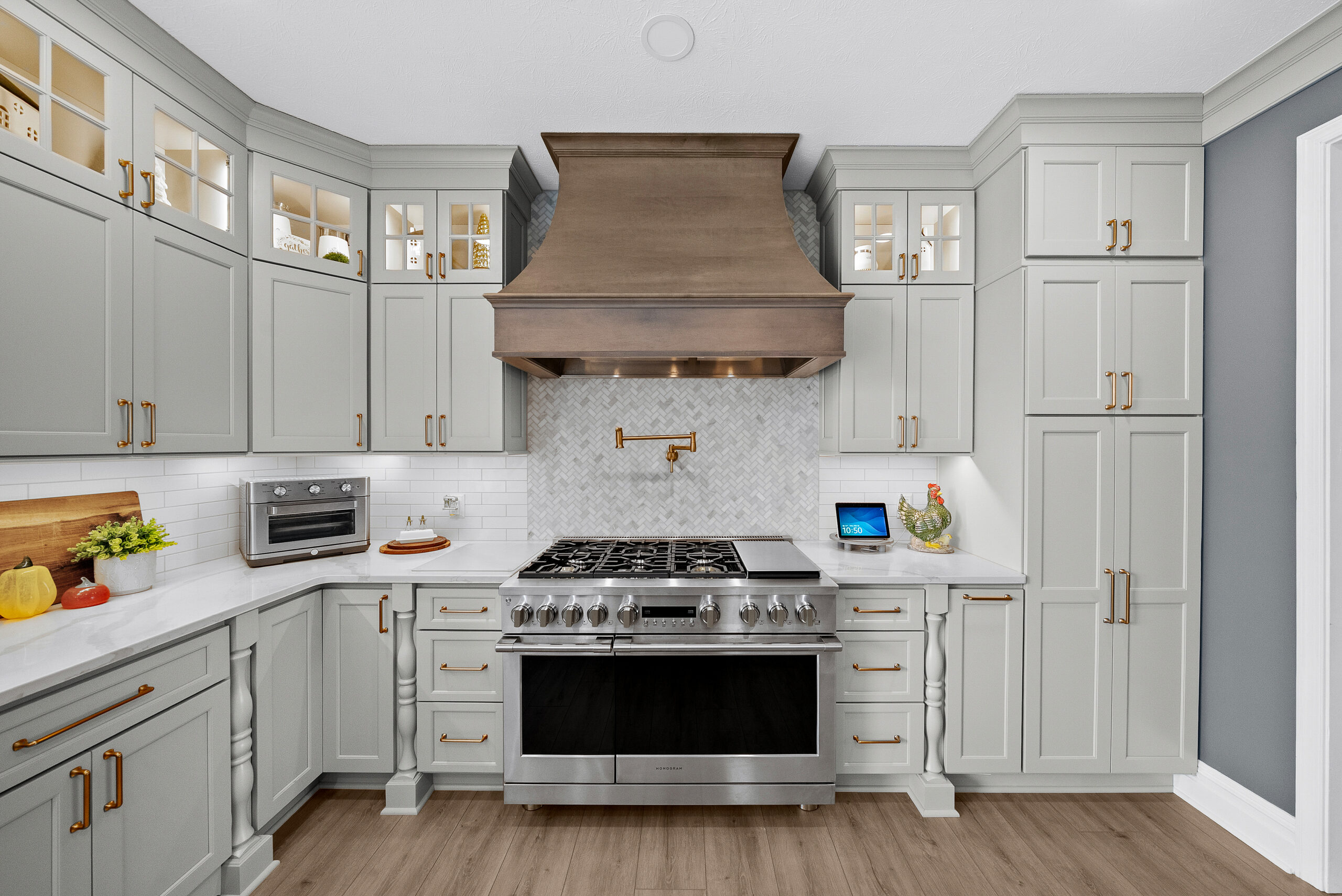 Bright Airy Baldwin Kitchen Showing a Light Quartz Countertop With Veining, Warm Tone Luxury Vinyl Flooring and Large Gray Island