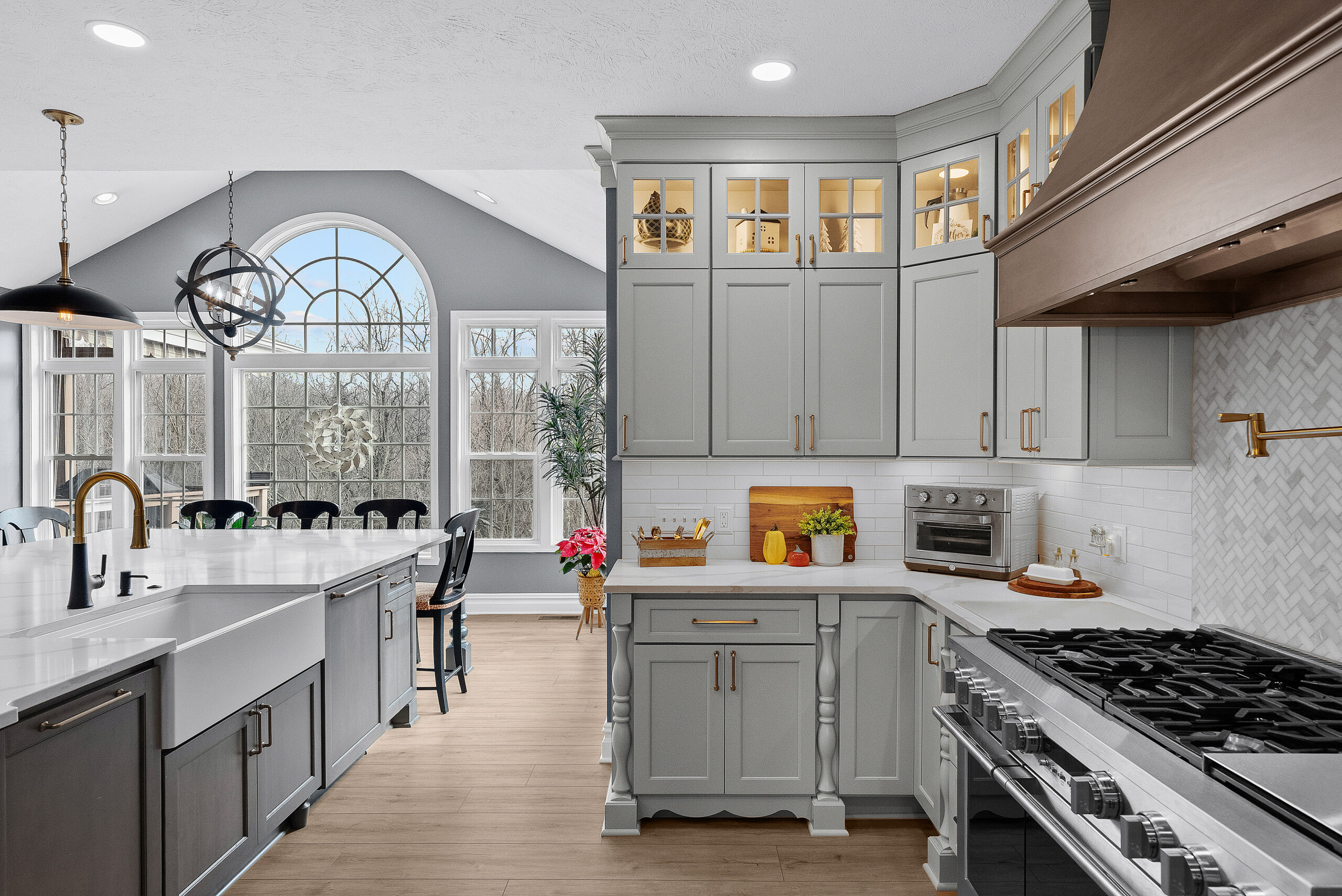 Bright Airy Baldwin Kitchen Showing a Light Quartz Countertop With Veining, Warm Tone Luxury Vinyl Flooring and Large Gray Island