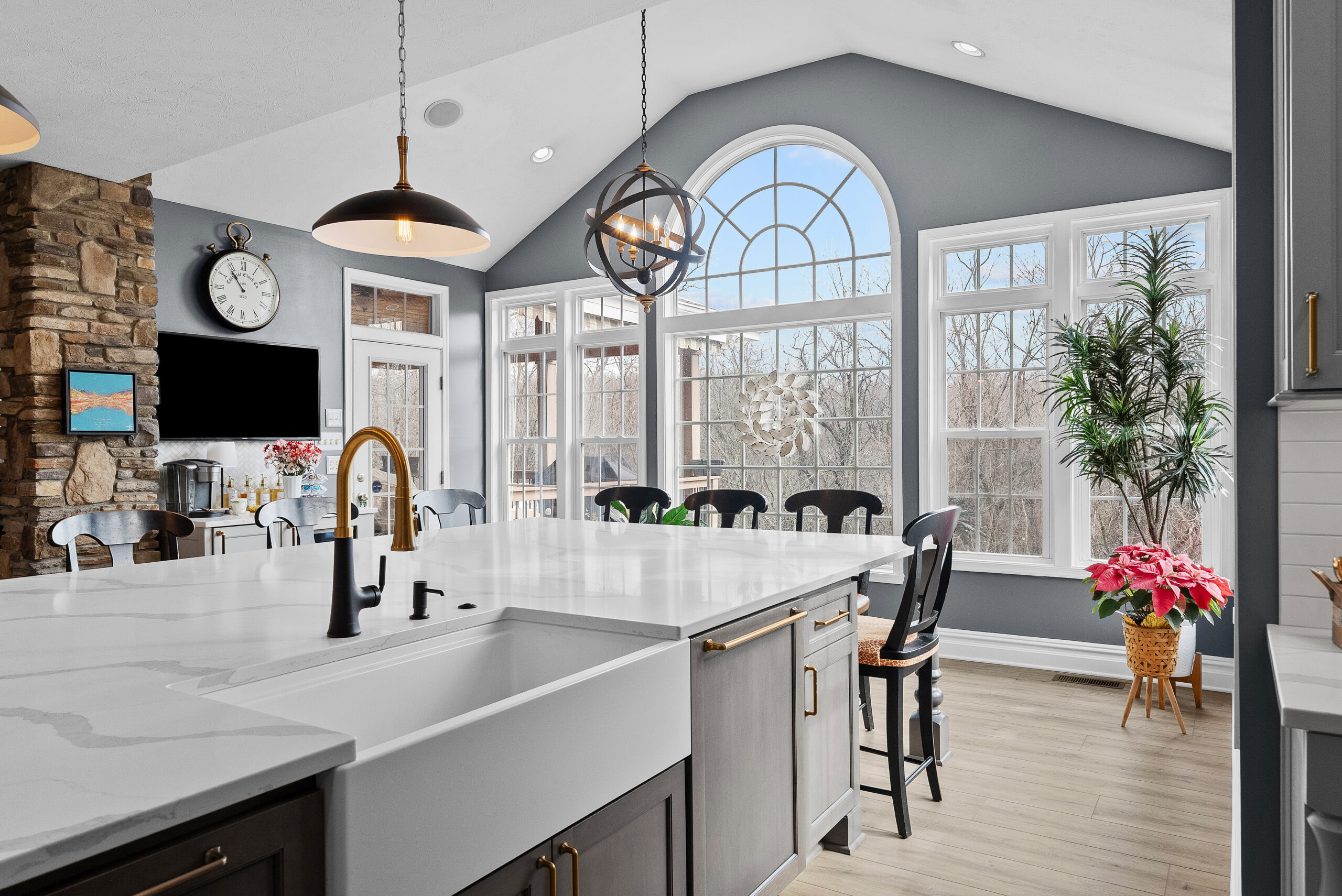 Bright Airy Baldwin Kitchen Showing a Light Quartz Countertop With Veining, Warm Tone Luxury Vinyl Flooring and Large Gray Island